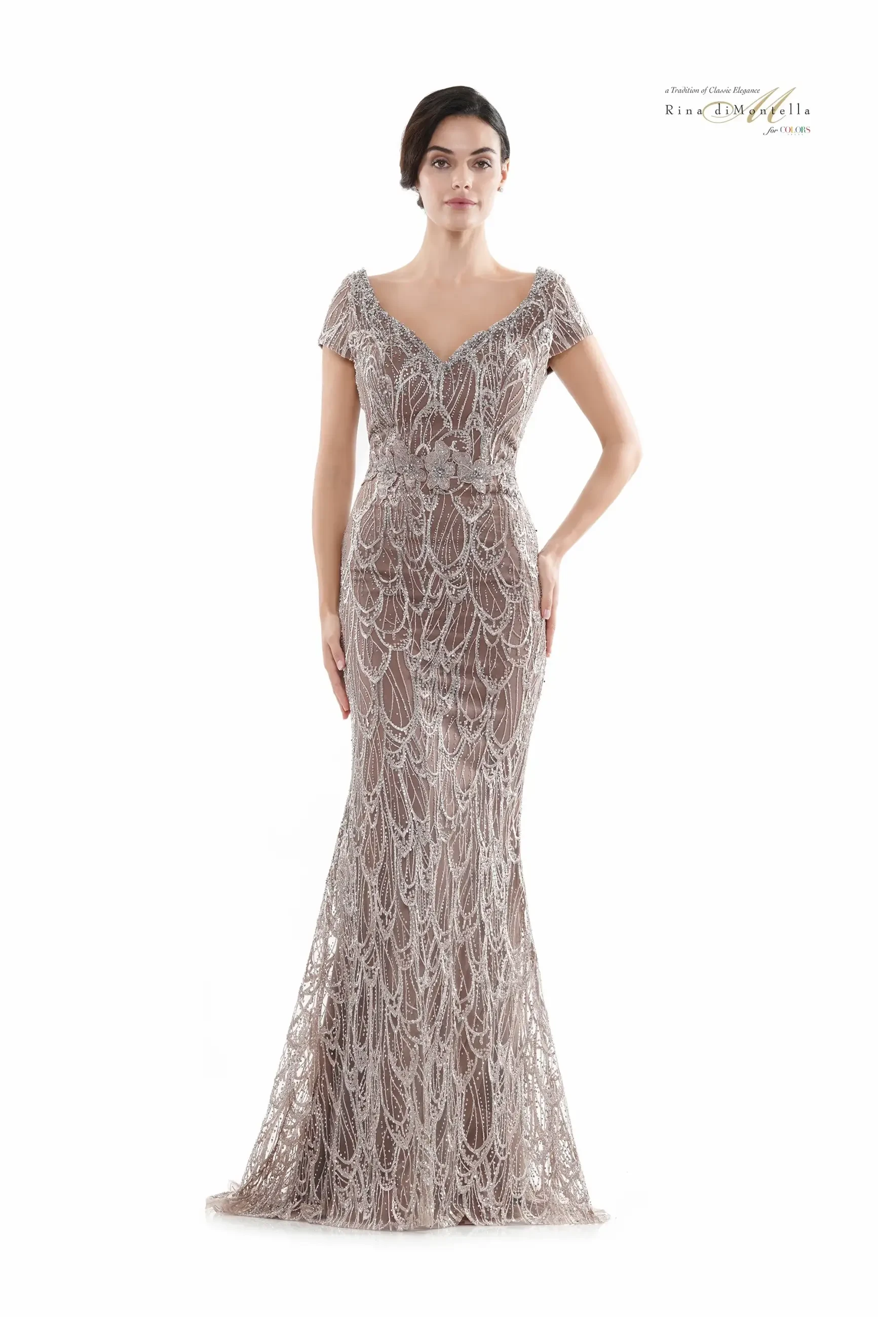 A woman is wearing a form-fitting, floor-length gown with intricate beadwork and a V-neckline. The dress has short sleeves and a mermaid silhouette, creating an elegant appearance.