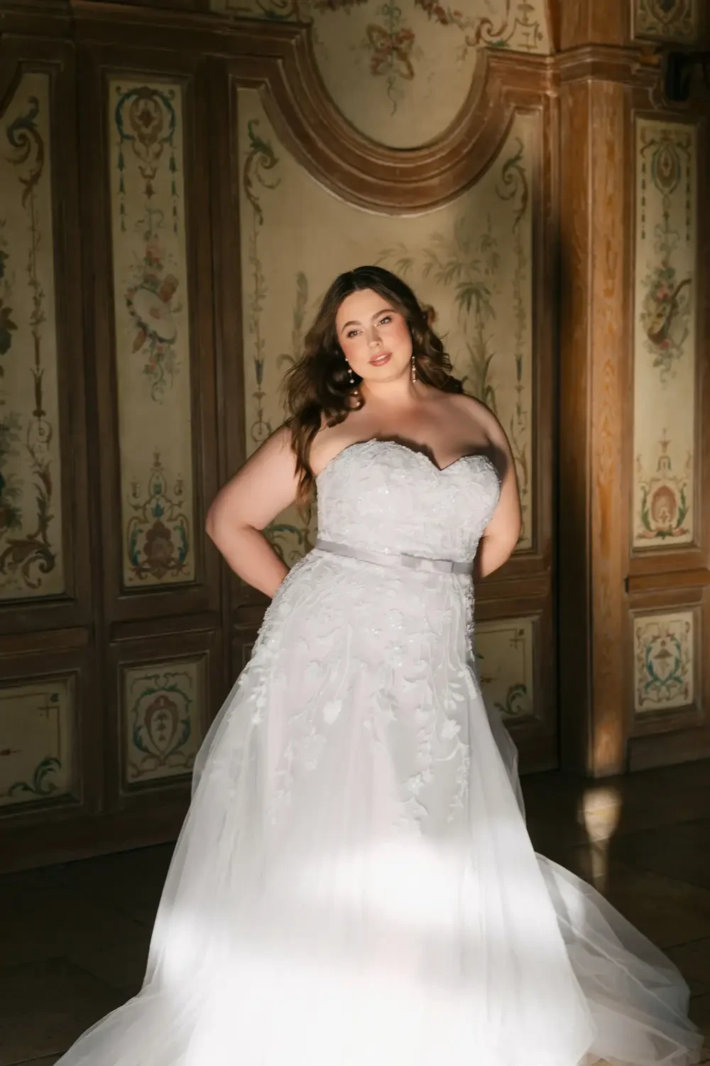 model is wearing a plus size strapless bridal gown